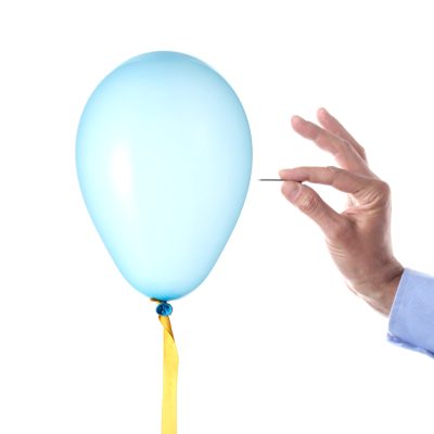 finance burst concept: caucasian man's hand holding a nail burst a party balloon isolated with clipping path